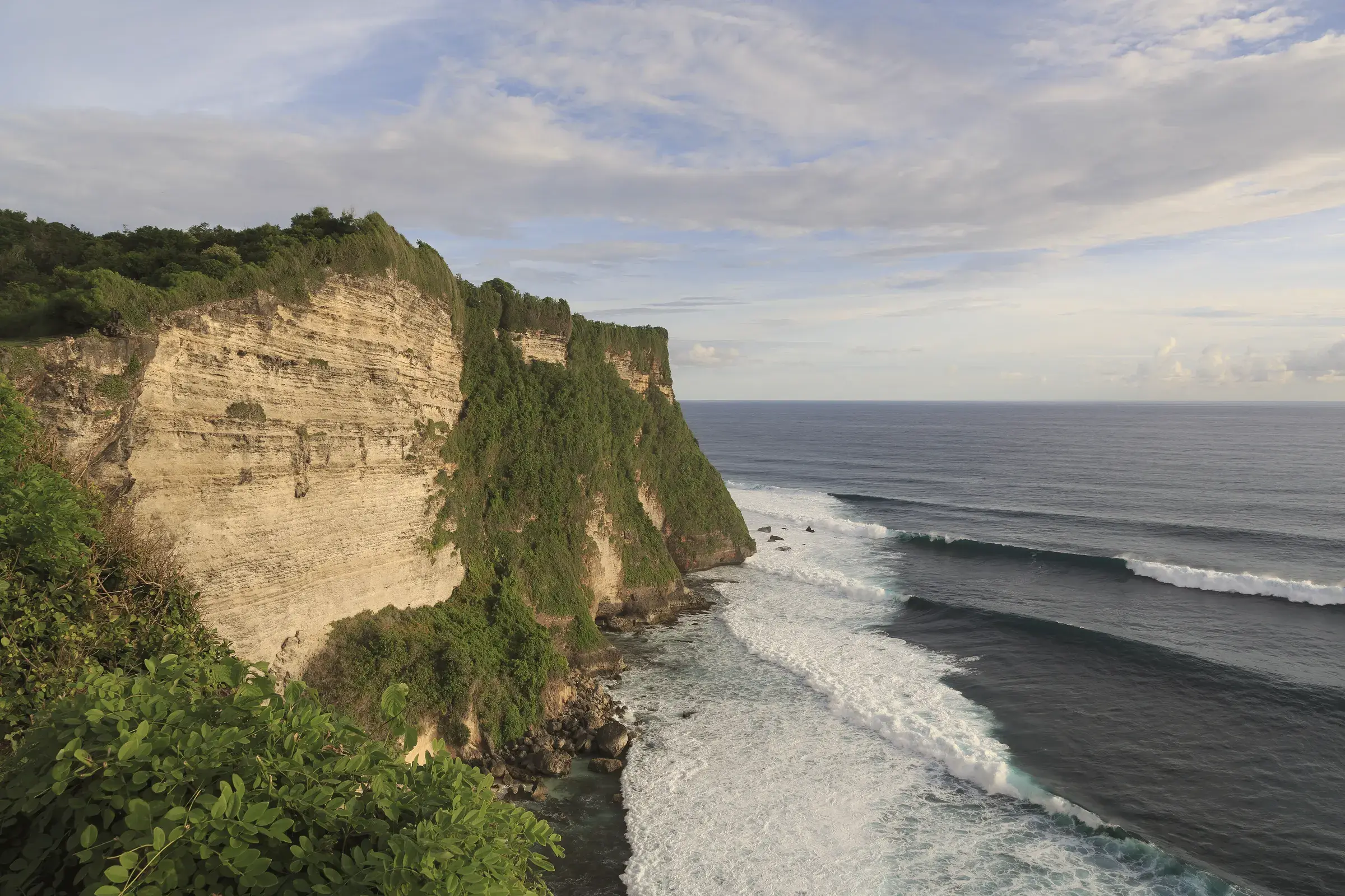 Limestone cliffs of Uluwatu dropping into the Indian Ocean, with long lines of surf