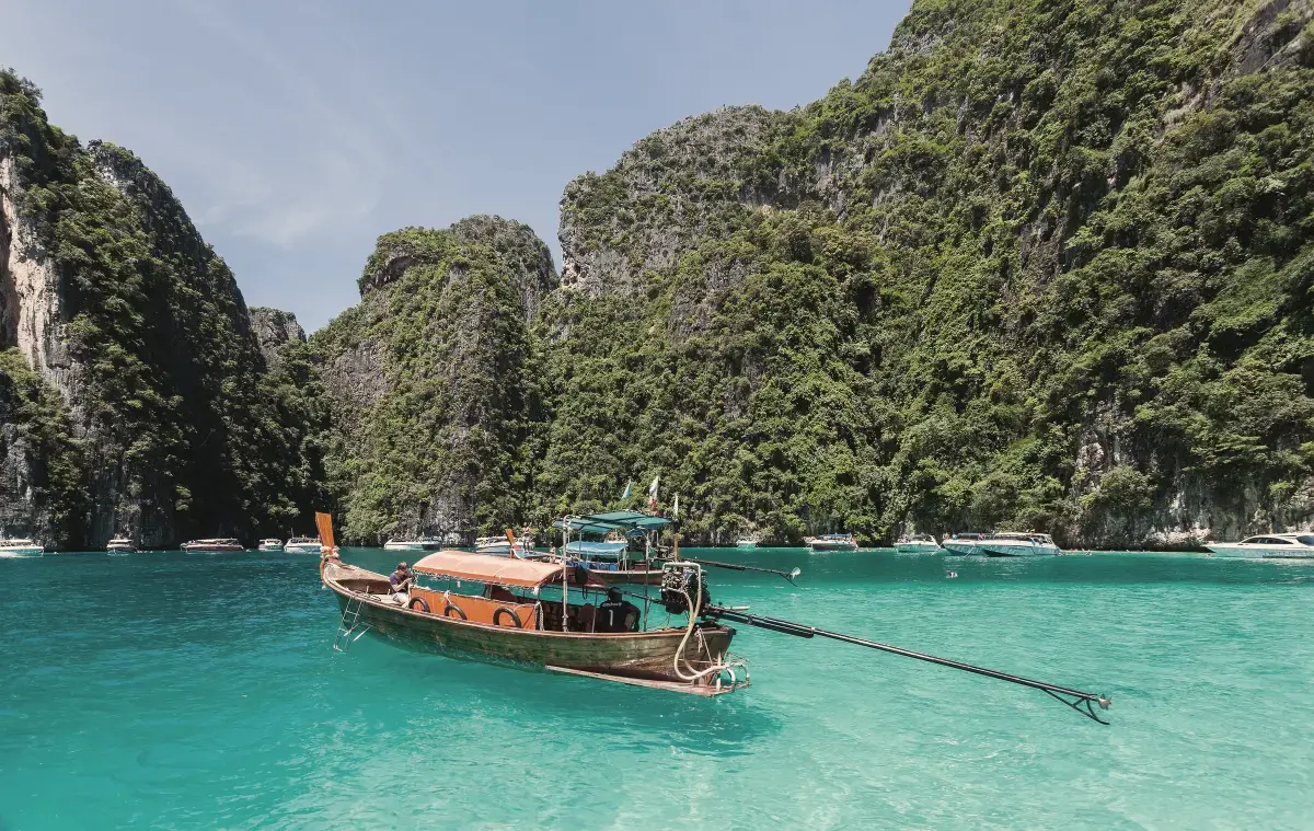Longtail boat on turquoise water below the limestone cliffs of Koh Phi Phi Leh