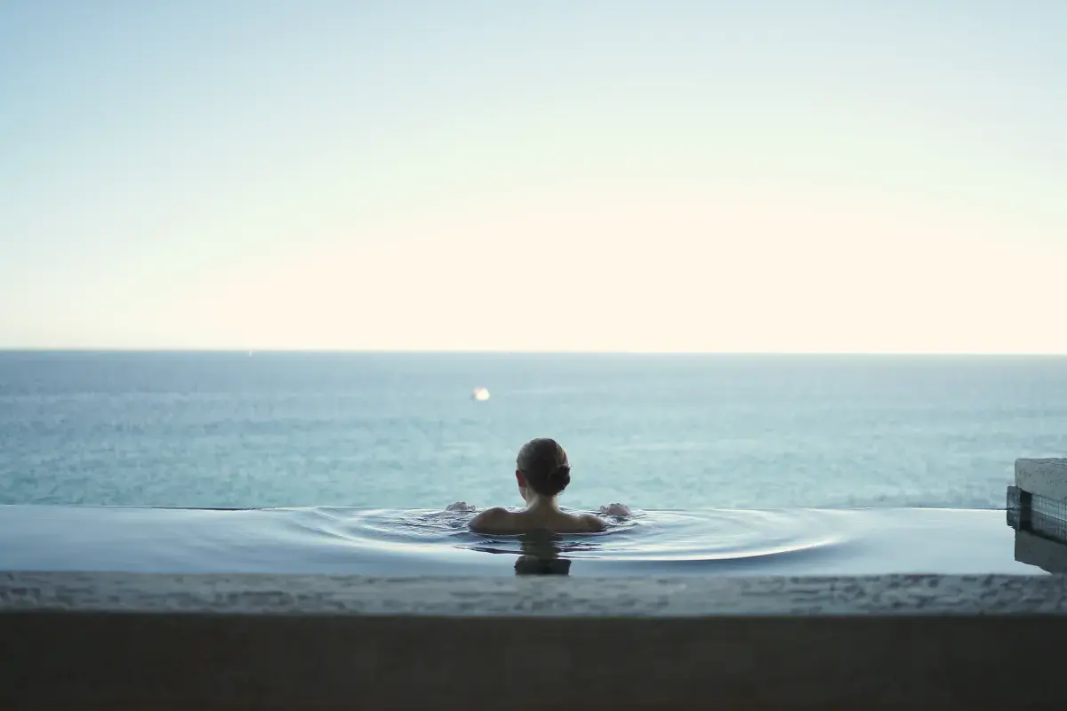 Swimmer seen from behind in an infinity pool facing the open sea